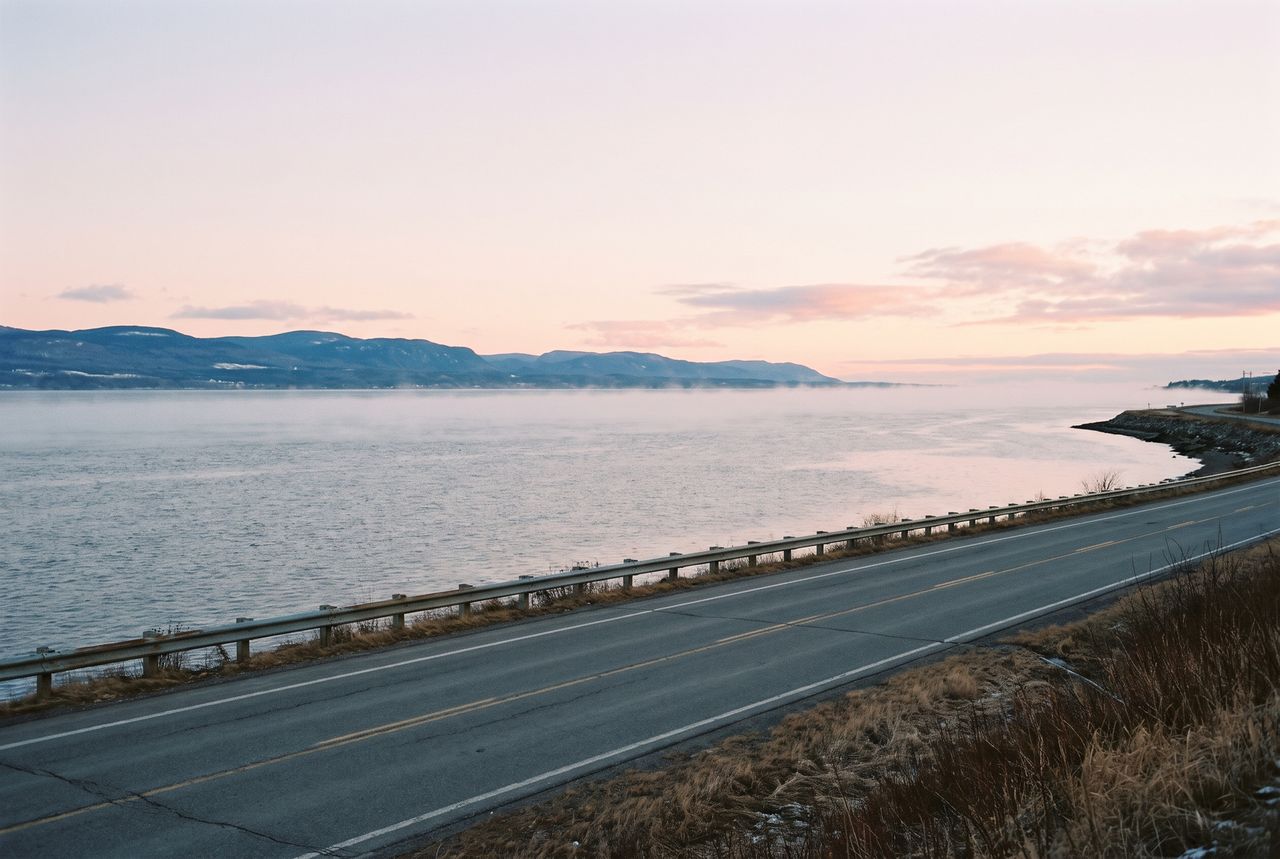 Le fleuve à l'aube, brume sur l'eau, rive lointaine et route déserte